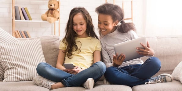 Two girls playing on devices. 