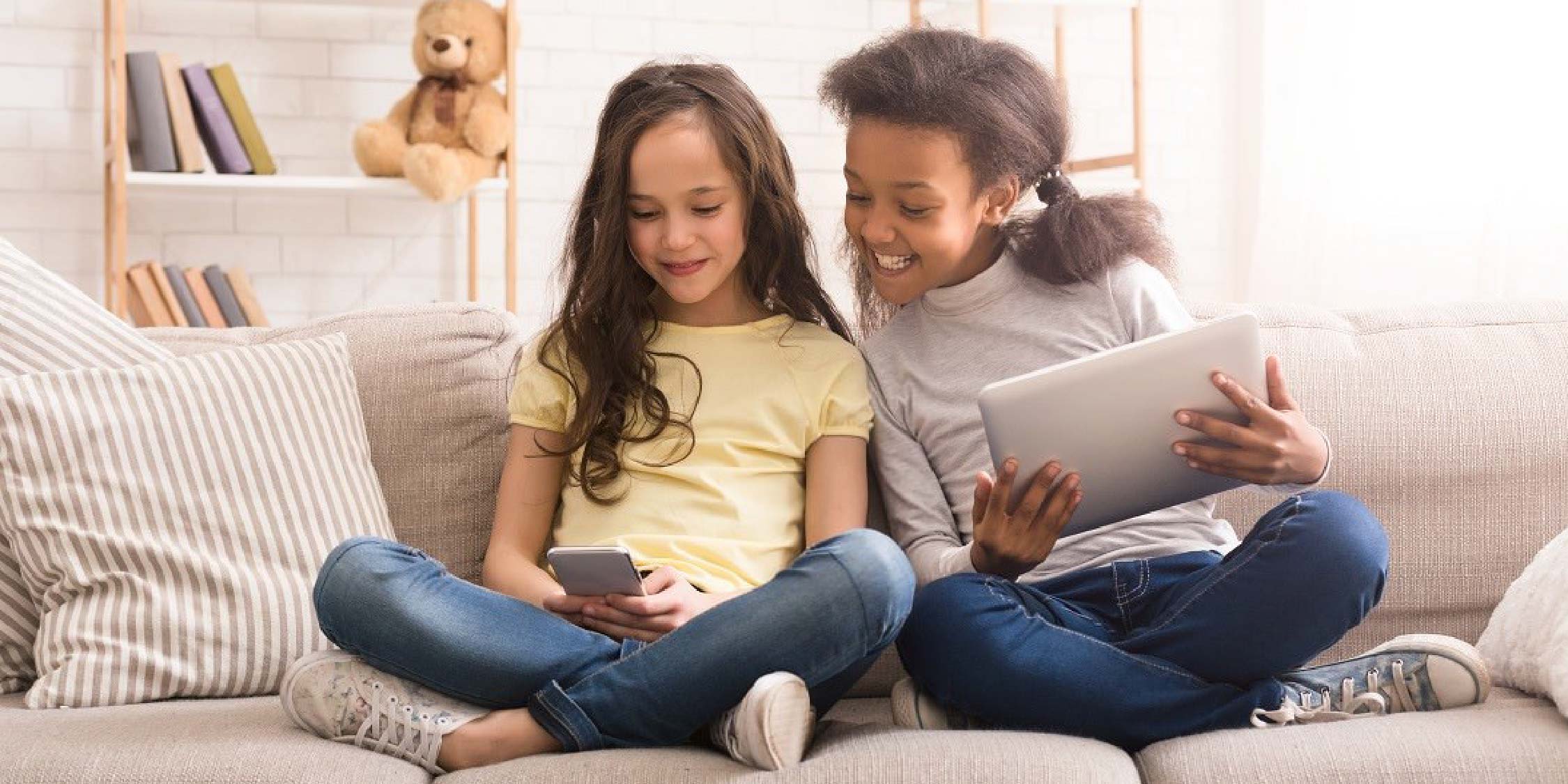 Two girls playing on devices. 